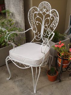 a white chair sitting on top of a patio next to potted plants and flowers