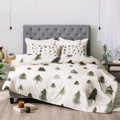 a bed with green trees on it in a room next to a white wall and wooden floors