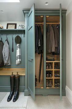 a walk in closet filled with lots of coats and boots next to a wooden bench