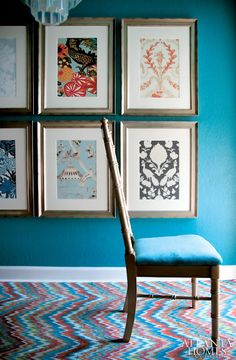 a chair sitting in front of a blue wall with pictures on the wall behind it