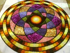 a circular stained glass window with an orange and purple flower in the center on a white surface