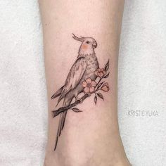 a small bird sitting on top of a tree branch with flowers around its neck and foot