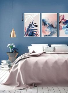 a bedroom with blue walls and paintings on the wall