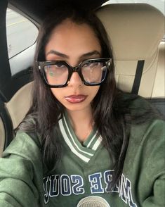 a woman wearing glasses sitting in the back seat of a car