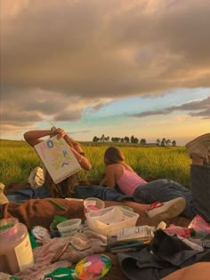 two people sitting on the ground with food and drinks in front of them, under a cloudy sky