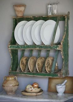 a shelf with plates and vases on top of it next to a wall rack