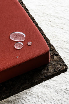 a red book sitting on top of a white floor next to a stone slab with drops of water