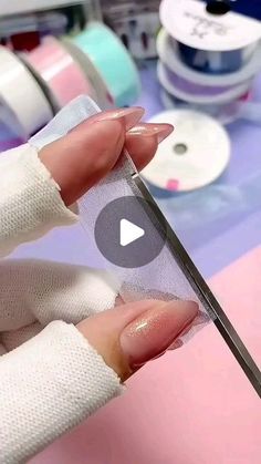 a woman is holding a pair of scissors in her left hand while she's working on some crafting supplies