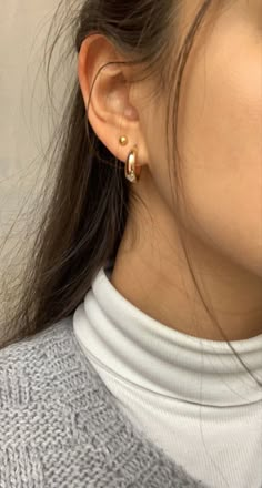 a close up of a person wearing some kind of gold earring on their left ear