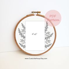 a cross stitch pattern with flowers and leaves in the hoop on a white wall background