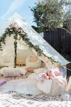 a teepee tent is set up with pillows and blankets on the ground in front of it