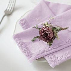 a purple napkin with a flower on it sitting next to a fork and spoons