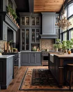 a large kitchen with gray cabinets and wooden floors, an island in the middle is surrounded by potted plants