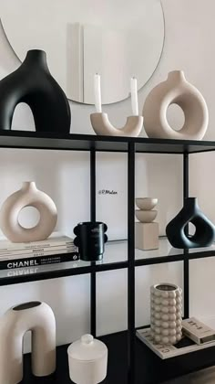 a shelf with vases and books on it in front of a wall mounted mirror