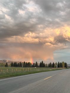 a rainbow appears in the sky over a highway