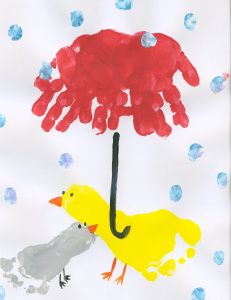 a child's hand holding an umbrella over a yellow duck