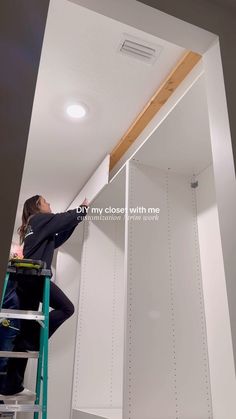 a man on a ladder working on the ceiling in a room with white walls and ceilings