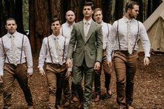 a group of men standing next to each other in front of a forest filled with trees