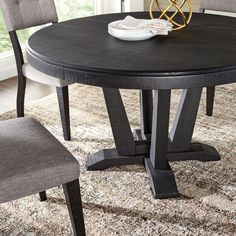 a dining room table and chairs with a rug on the floor in front of it