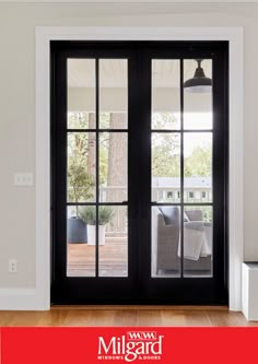 an open door with black glass and wood flooring in front of a white wall