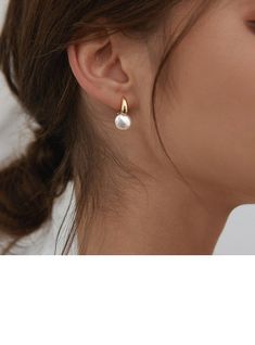 a close up of a woman's face wearing gold earrings with pearls on them