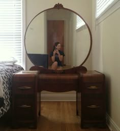 a woman taking a selfie in front of a mirror on a desk with a laptop