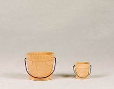 two wooden buckets sitting next to each other on a white surface with one in the foreground