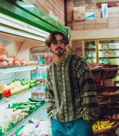 a man standing in front of a display of fruits and vegetables at a grocery store