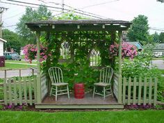 an outdoor gazebo with two chairs and flowers