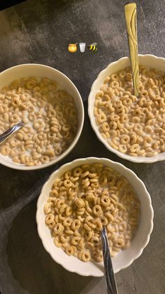 three white bowls filled with cereal on top of a table