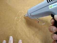 a person using a hair dryer on top of a wooden table next to their nails