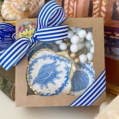 a blue and white box with cookies in it on a table next to seashells