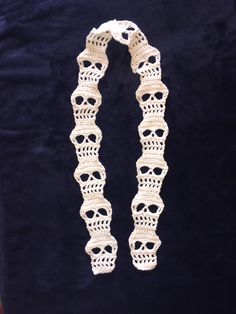 a white crocheted necklace on a black velvet background, with two skulls in the middle