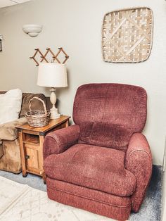 a living room with a red recliner next to a small table and lamp on top of it