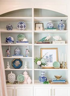 a white bookcase filled with lots of blue and white vases on top of it