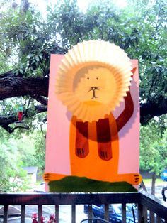 a lion paper plate craft on top of a table in front of a green tree