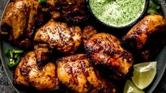 grilled chicken with green sauce and garnishes on a black platter