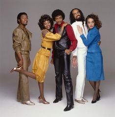 four people standing together in front of a white background