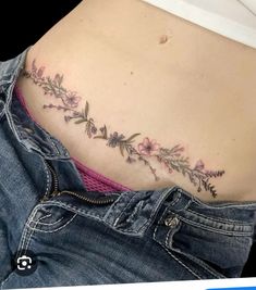 a woman's stomach with flowers and leaves on the side, in front of her belly