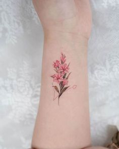 a small pink flower tattoo on the wrist