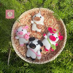 small crocheted animals are sitting in a basket on the grass next to each other