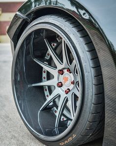 the front wheel of a sports car with chrome spokes