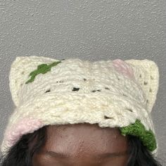 a close up of a person wearing a knitted cat hat with leaves on it