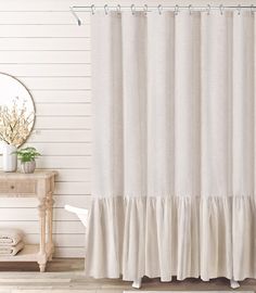 a white shower curtain with ruffles on the bottom is in front of a mirror