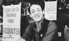 a black and white photo of a man sitting in front of a sign that says don't let the happen here register