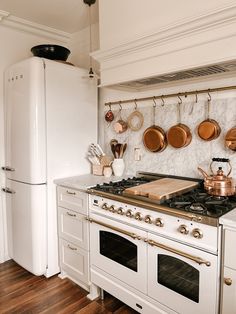 a kitchen with an oven, stove and pots hanging on the wall next to each other