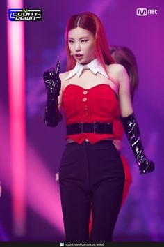 a woman with red hair and black gloves on the catwalk at a fashion show