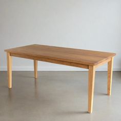 a wooden table sitting on top of a floor next to a white wall in an empty room