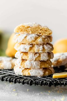 a stack of powdered sugar cookies sitting on top of a cooling rack next to lemons