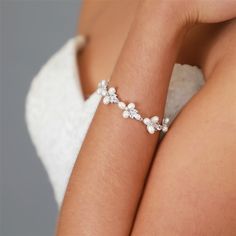 a woman's arm wearing a bracelet with flowers and pearls on the end of it